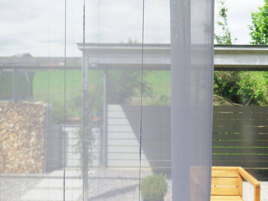 Weisser Vorhang am Küchenfenster mit Ausblick auf Sitzplatz